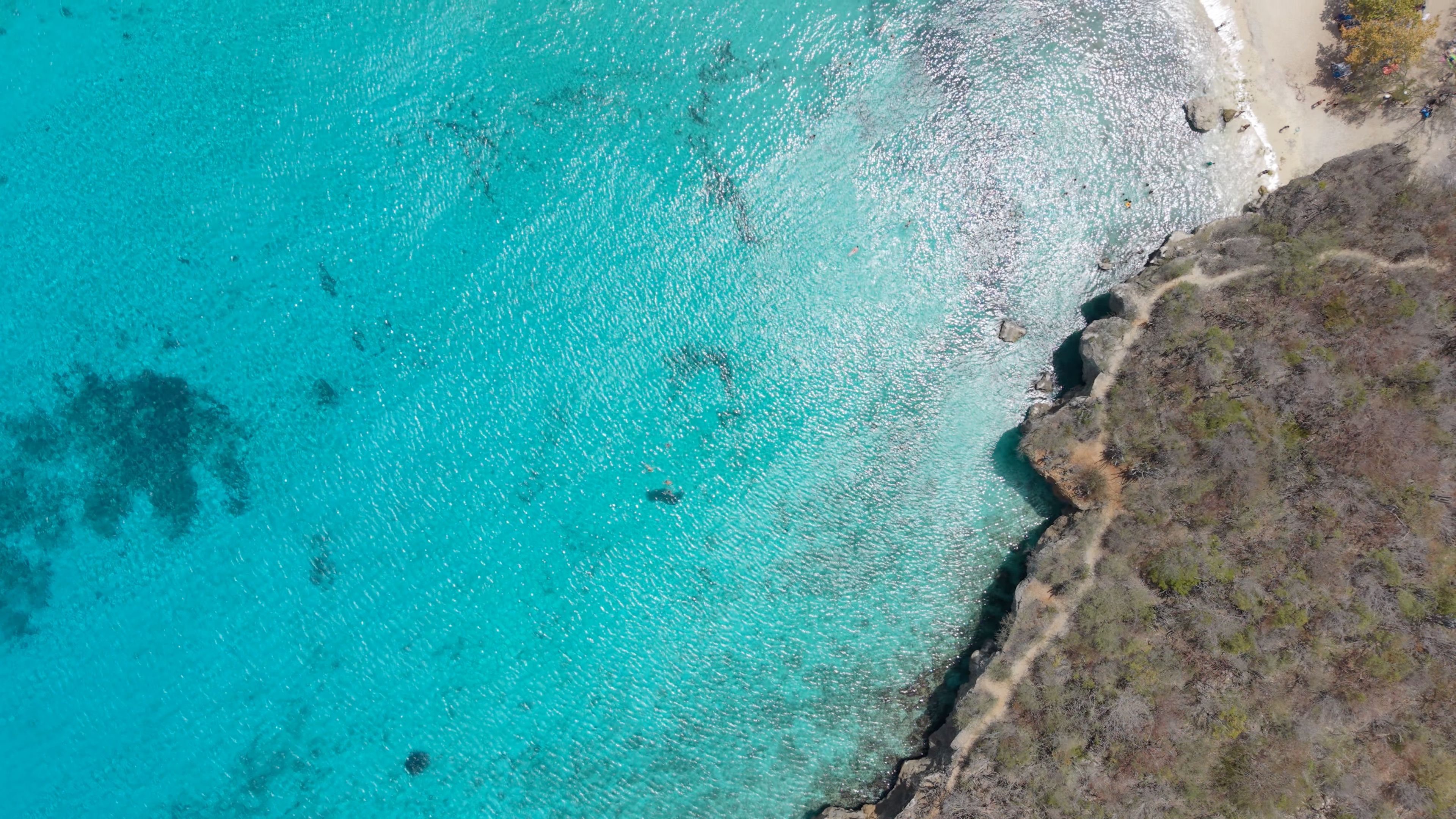 Kleine baai met wit strand, parasols en helder turkoois water, van boven gezien